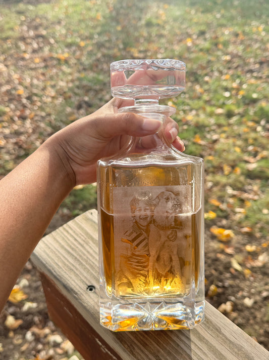 Hand holding an engraved decanter outdoors in natural light