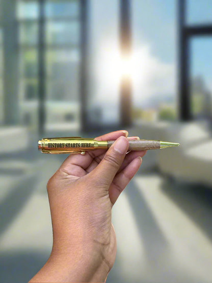 Hand holding a Signature Series brass pen in natural light