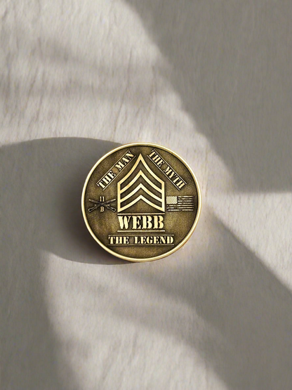 Brass challenge coin engraved with a name and rank, overhead view
