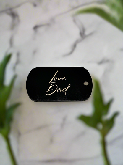 Engraved black dog tag keychain on a marble surface
