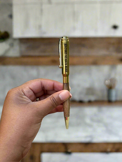 Hand holding a 30.06 brass casing pen with engraved lettering