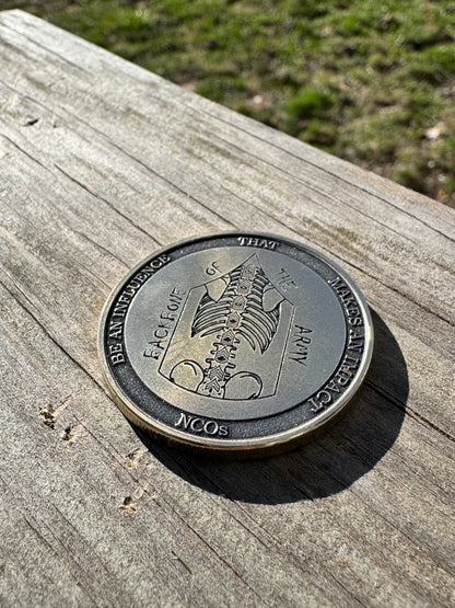 Engraved challenge coin resting on weathered wood outdoors
