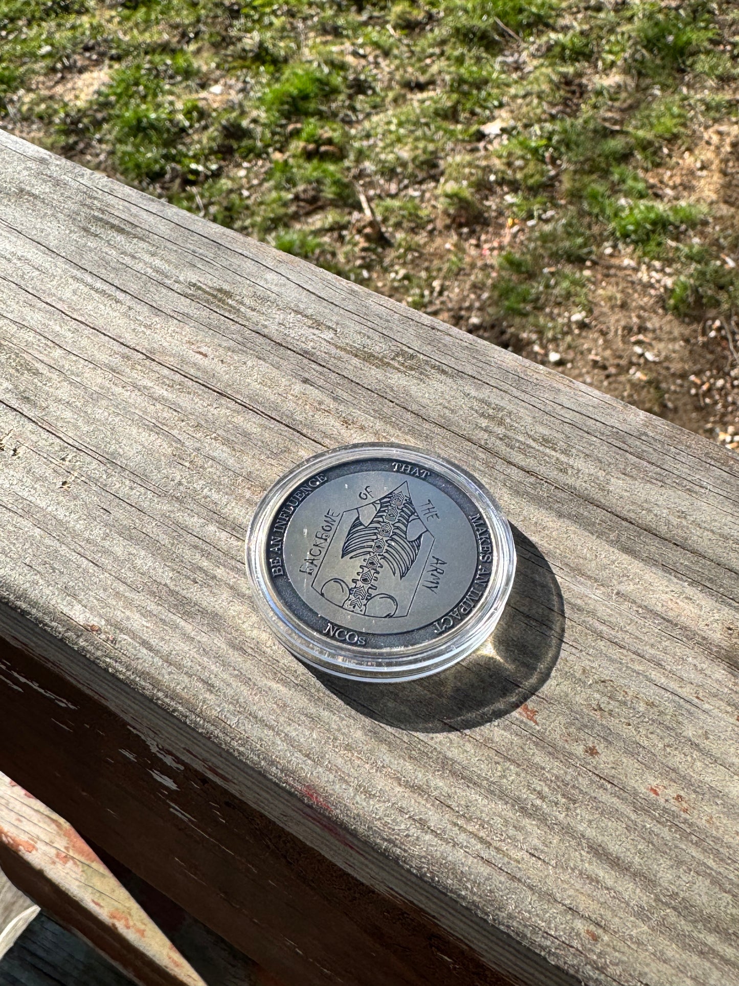 Silver challenge coin standing on edge on a wood surface
