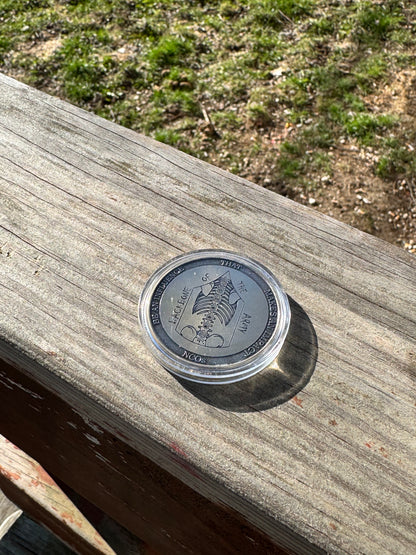 Silver challenge coin standing on edge on a wood surface