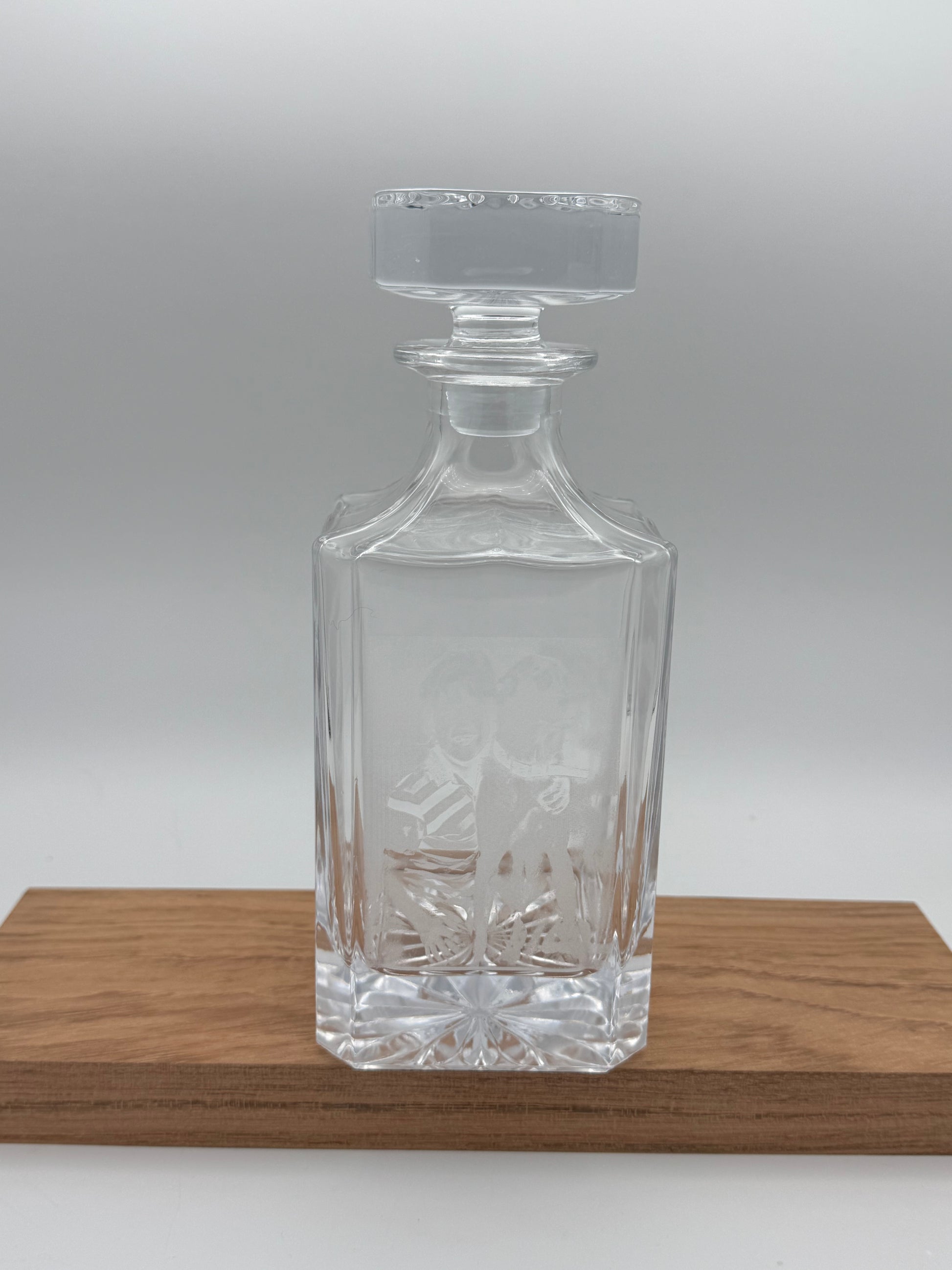 Empty engraved glass decanter on a walnut board