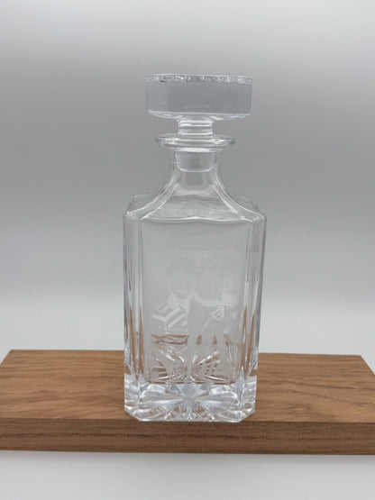 Empty engraved glass decanter on a walnut board