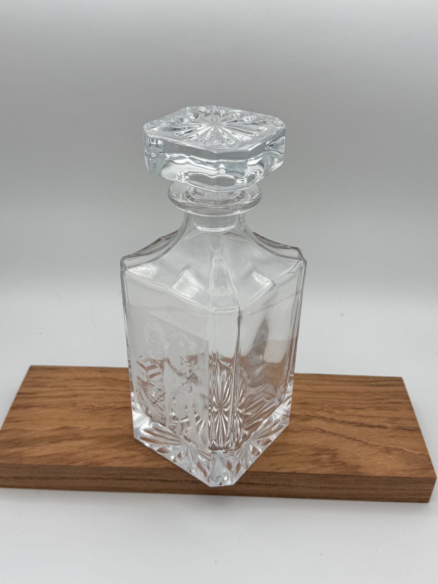 Clear glass decanter with fitted stopper on a walnut surface