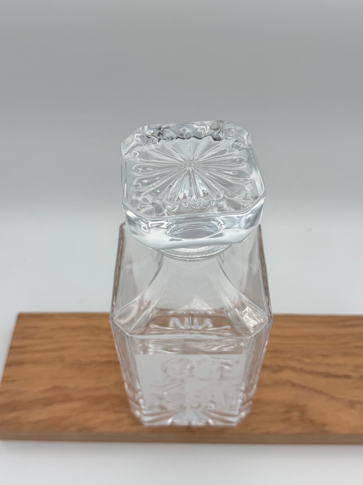 Square glass decanter with stopper, side view on a wood board