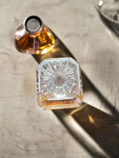 Engraved decanter and glass stopper casting light on a stone surface