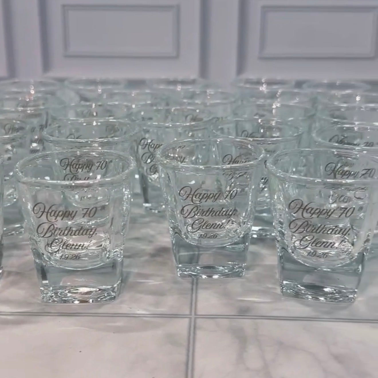 Bulk engraved shot glasses arranged for a birthday celebration