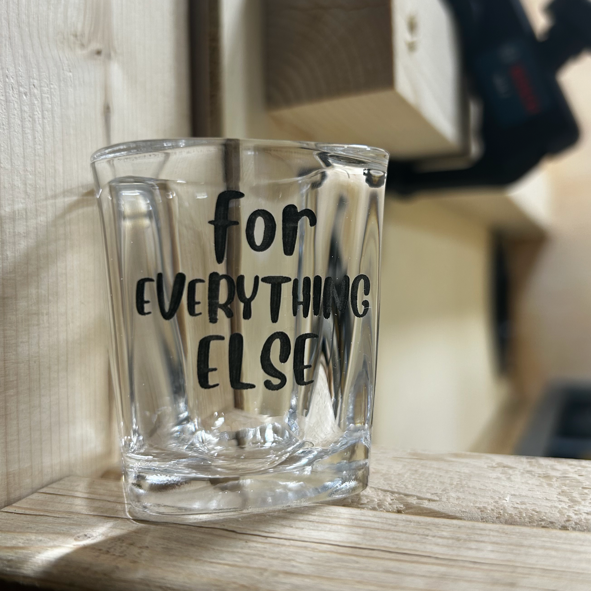 Engraved shot glass reading For Everything Else on a wood shelf
