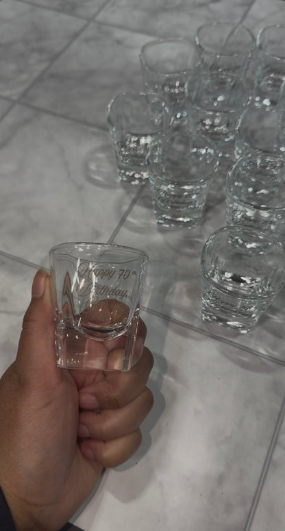 Hand holding an engraved shot glass with a bulk order behind