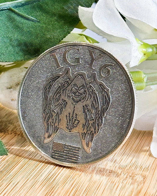 Antiqued challenge coin with detailed engraving beside white flowers
