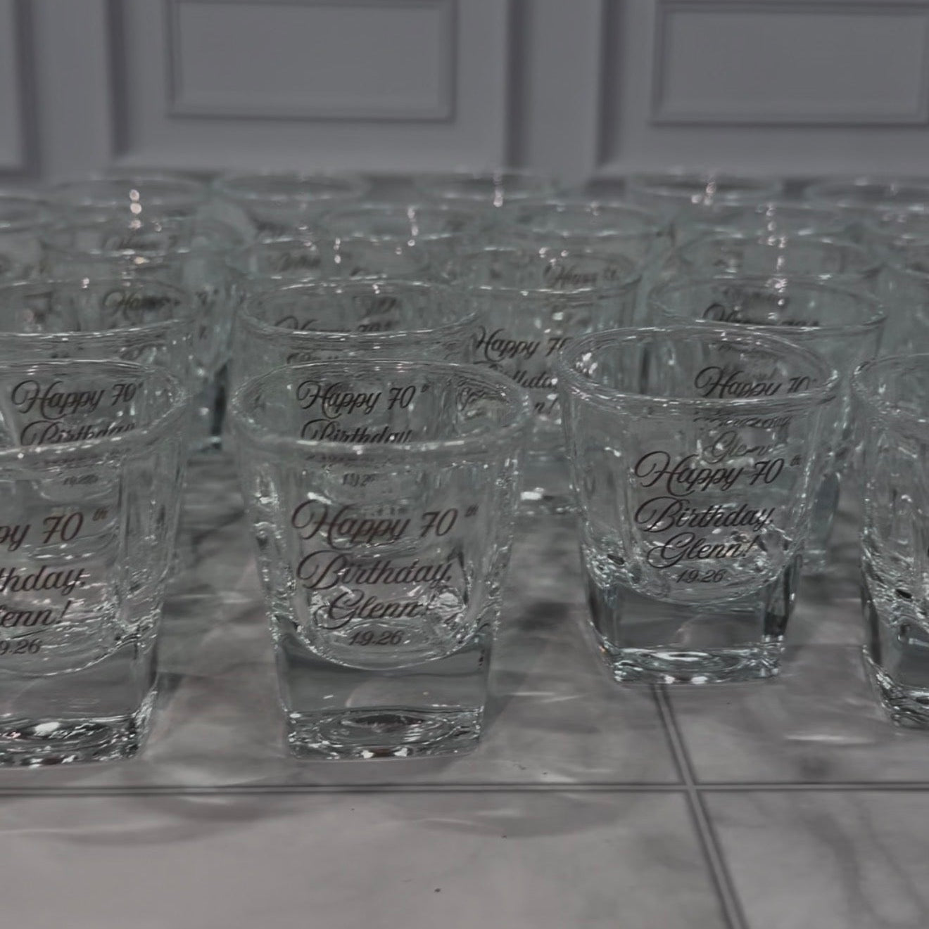 Rows of custom engraved shot glasses from a bulk birthday order